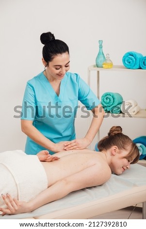 therapist makes a therapeutic back massage in the spa