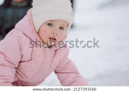 Little girl in pink walks outdoors on winter snowy day. High quality photo