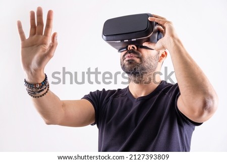 Young man using VR glasses headset gesturing with hands, portrait on light background. Virtual reality, future technology, education video gaming.