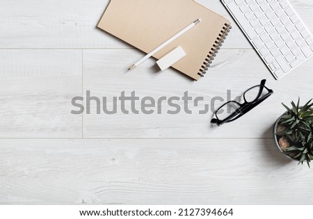 Office supplies on wooden floor. Notebook, glasses, pencil, eraser, keyboard and succulent plant. Flat lay.