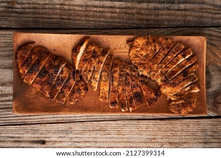 Fried blackened chicken breast on a wooden board Royalty-Free Stock Photo #2127399314