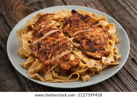 Closeup of blackened chicken breast on fettuccine with Alfredo sauce Royalty-Free Stock Photo #2127399458