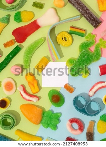 marmalade sweets, a background of various kinds of jelly sweets in the form of bears, ribbons, fruits and other toys. Sweets in a toy basket. Centered white card space for your ad