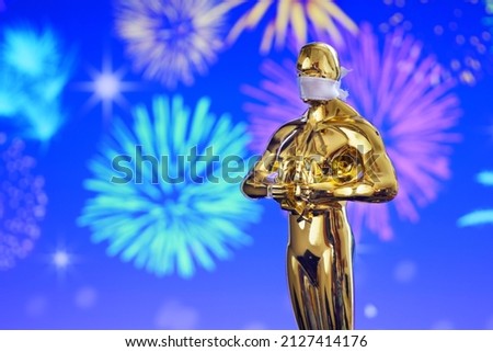 Hollywood Golden Oscar Academy award statue in medical mask on fireworks background. Success and victory concept. Oscar ceremony in coronavirus covid-19 time