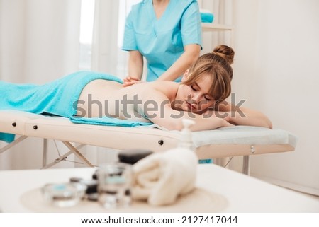 a massage therapist gives a therapeutic back massage to the patient