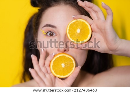young brunette woman girl with slice of orange fruit near skin face on yellow background. tasty juicy fruit. Tropical fruits, Healthy food. citrus slice. tasty juicy fruit. Royalty-Free Stock Photo #2127436463