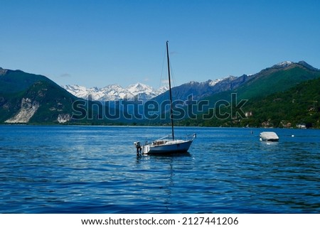 Sailing boat on lake Maggiore with snowy mountains in the background. Piedmont, Italy. High quality photo