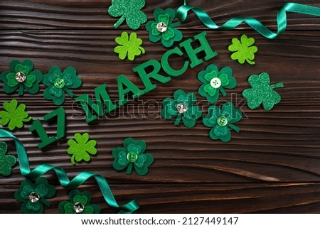 Handmade felt Shamrock leaves and letters 17 march on dark flat lay wooden background