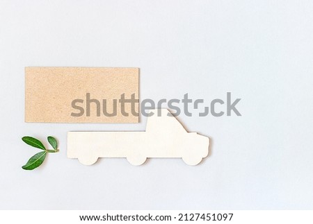 wooden figurine of a car with a green leaf on a gray background. Ecology concept