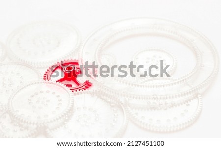 red gear lies among the transparent gears on a white background