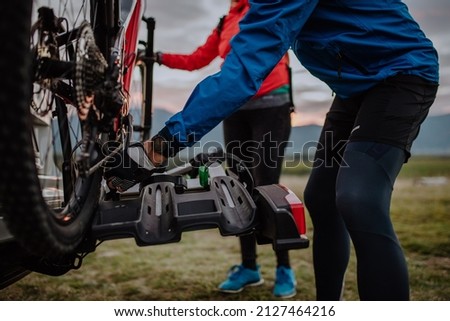 Active senior couple loading their bicycles on car carrier outdoors in nature in autumn day. Royalty-Free Stock Photo #2127464216