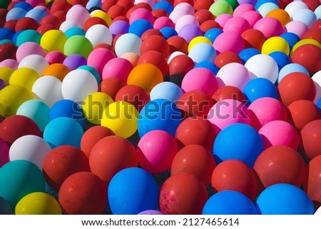 Various colorful ballons floating on a water pool.