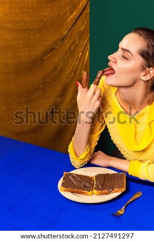Food pop art photography. Young girl tasting sweet chocolate toasts isolated over vintage style interior. Concept of food, creativity. retro 80s, 70s style. Complementary colors, Copy space for ad