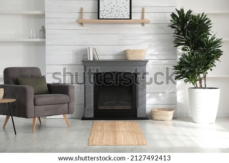 Cozy living room interior with comfortable armchair and modern electric fireplace