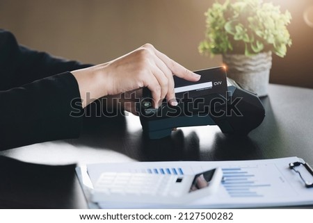 Safe technology concept from using credit card, employee is holding customer's credit card to pay for service or payment via electronic card swipe machine