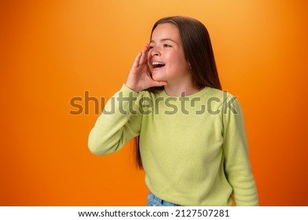 Teenager girl screaming news on orange studio background