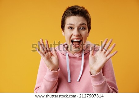 Surprised happy beautiful woman looking in excitement over yellow background