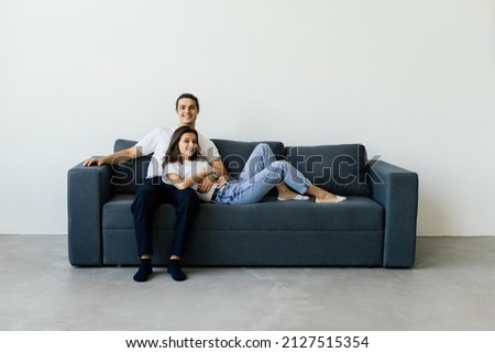 Portrait of couple in love posing seated on couch in modern studio apartments, concept of capture happy moment, harmonic relationships, care and sincere feelings Royalty-Free Stock Photo #2127515354
