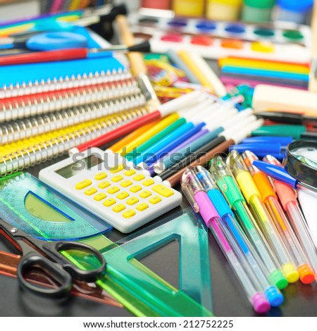 Black desk's surface covered with multiple stationery office supplies as a background back to school composition