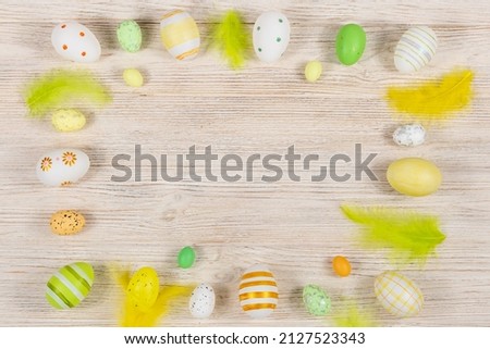 Top view of Easter eggs painted with different patterns and feathers on a wooden background. Copy space. Place for an inscription.