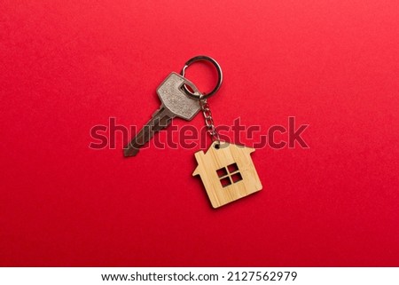 Keys with house-shaped keychain on color background.