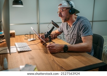 Middle-aged Blogger man in headphones reading text recording voice or making online webinar or news announcement. Modern home sound studio audio recording or live streaming technology concept.