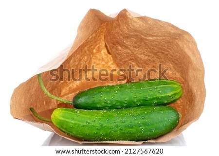 Two ripe green cucumbers in a paper bag, macro, isolated on a white background.