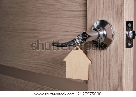 Key with a keychain in form house in door lock an open door.Concept theft and burglary apartments and private property