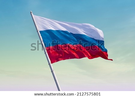 Flag of Russia against the yellow-blue sky at dawn. Escalation of the conflict. Abstract collage.