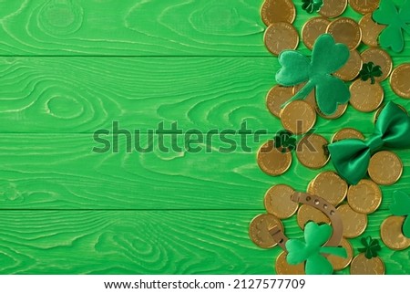 Top view photo of the many golden coins silk bow tie bronze horseshoe and confetti in shape of clovers on the wooden green isolated background blank space