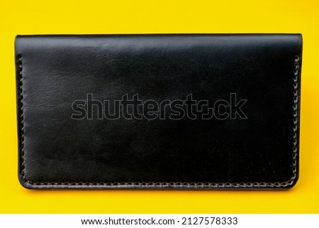Leather black purse book on a yellow background. Copy space for text or inscription