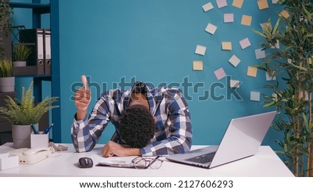 Exhausted worker putting head on desk and showing thumbs up sign, working overtime and feeling tired. Overworked man doing okay gesture with hand, waiting to take break from financial work.