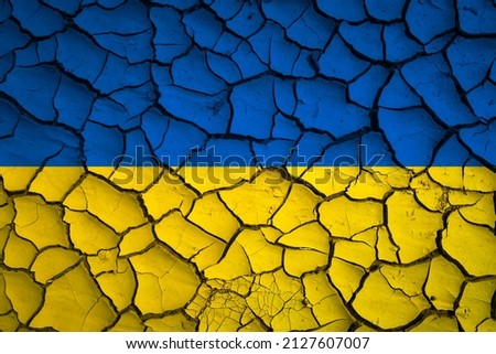 Ukraine national blue and yellow flag on a mud texture of dry cracks on the ground Royalty-Free Stock Photo #2127607007
