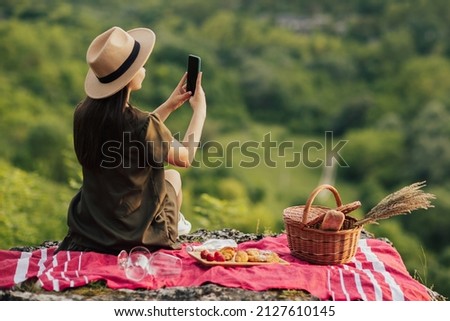 
Woman with hat using her mobile phone for take the picture at beautiful landscape in the mountain. Picnic in the mountain.
