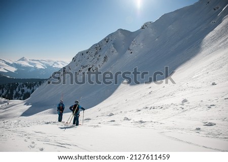 beautiful view of the snow-capped mountain slope and skiers with backpacks and skis on their backs. Ski touring and freeride concept