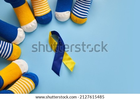 World Down syndrome day background. Down syndrome awareness concept. Socks and ribbon on blue background Royalty-Free Stock Photo #2127615485
