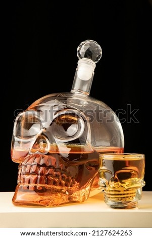 close-up black background high alcohol whiskey filled Transparent glass decanter carafe skull shot glass alcohol set