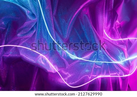 Pink and blue neon lights with glitter fabric background. Cyberpunk futuristic template. Royalty-Free Stock Photo #2127629990