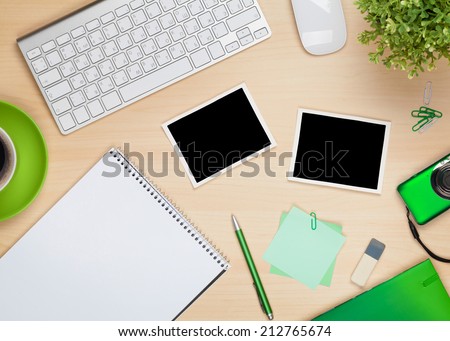 Photo frames on office table with notepad, computer and camera. View from above