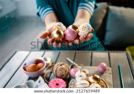 Female hands holding Easter painted Eggs, ready for decoration. Coloring chicken egg in pastel pink and golden color 