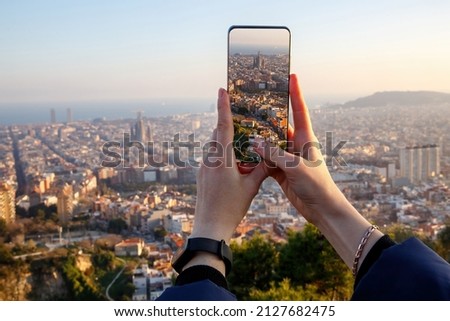 Travel concept - tourist taking a photo of Barcelona skyline on a mobile phone, Spain