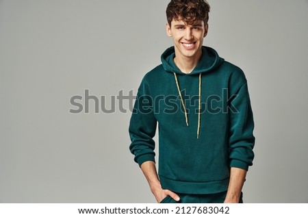 Portrait of cheerful young man in green hoodie isolated on gray background Royalty-Free Stock Photo #2127683042