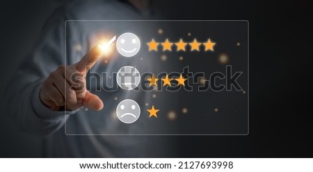 Customer satisfaction and service quality survey, Businessman pointing a smiley face icon to assess satisfaction with product and services on a virtual screen, highest level, positive feedback. Royalty-Free Stock Photo #2127693998