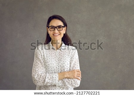 Happy confident smiling caucasian woman looking at camera studio headshot portrait. Casual positive lady showing cheerful emotion sanding on grey background. Feminine and youth, people expression Royalty-Free Stock Photo #2127702221