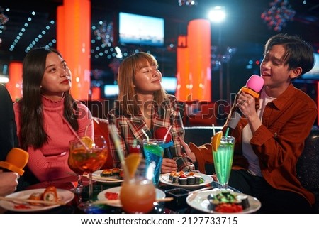 Group of friends having fun and singing songs at karaoke club, Social gathering event and nightlife entertainment concept, friends singing at karaoke, Group of young people enjoying at a nightclub