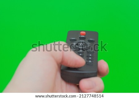 TV control panel in a male hand on a green background