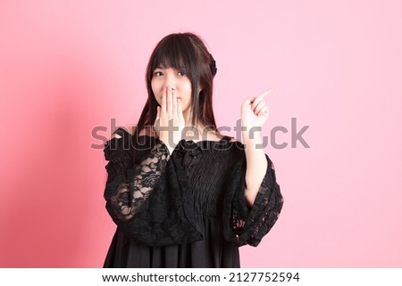 The cute young Asian girl with gothic dressed standing on the pink background