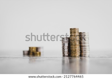stacks of different coins divided between a small and a big group on white background, concept of good vs bad investements or before and after investing
