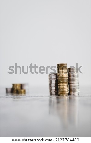 stacks of different coins divided between a small and a big group on white background, concept of good vs bad investements or before and after investing