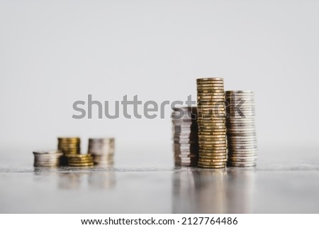 stacks of different coins divided between a small and a big group on white background, concept of good vs bad investements or before and after investing Royalty-Free Stock Photo #2127764486